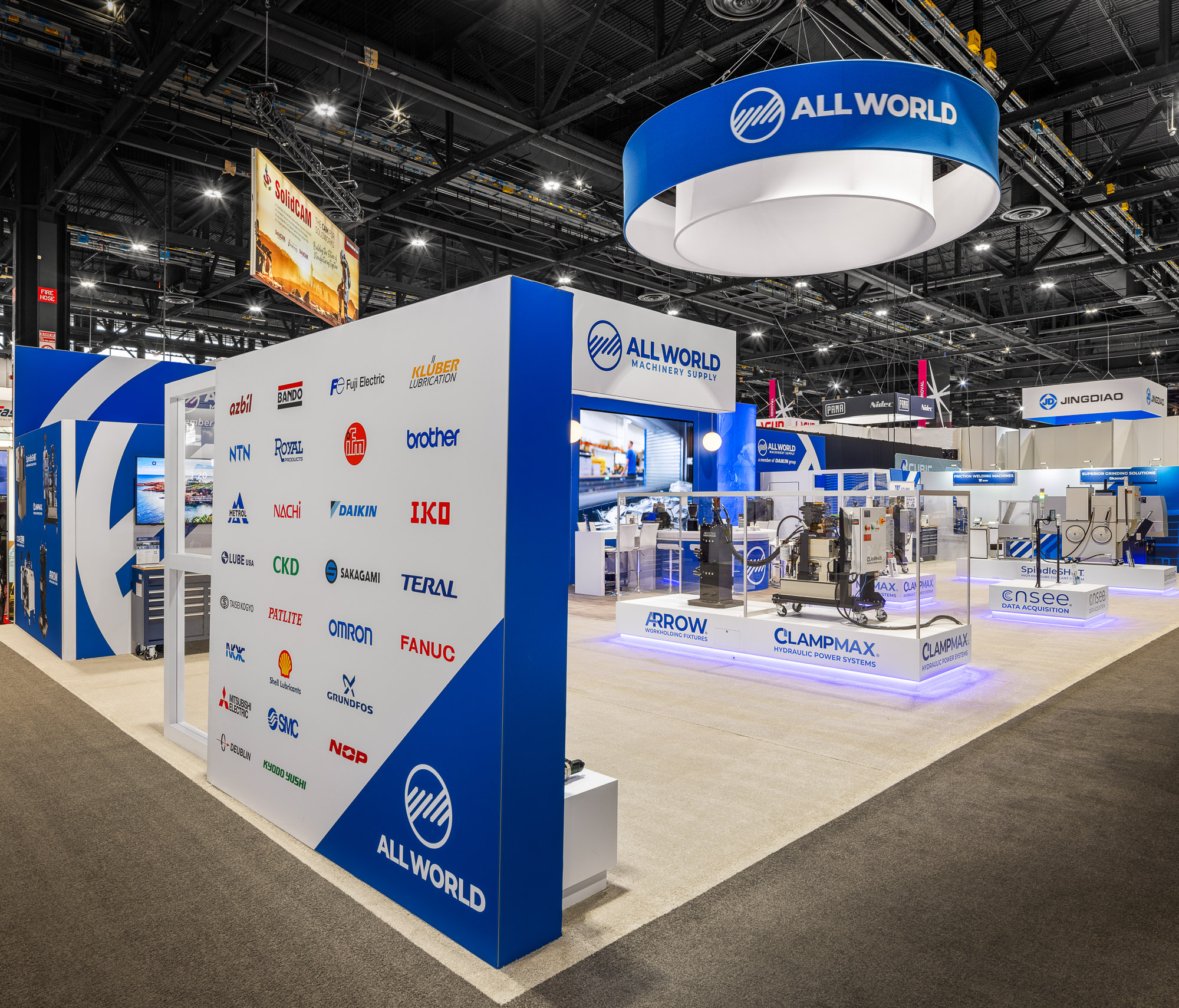 All World Machinery booth wide view with overhead hanging sign and product demo zones