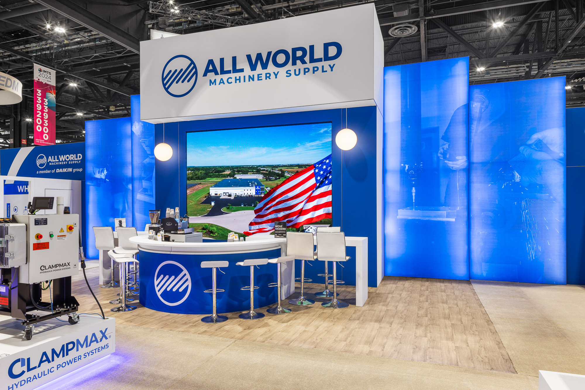 All World Machinery booth detail featuring branded graphic tower and meeting area